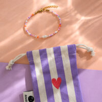 Perlenarmband flieder/rosa, mit Karabinerverschluss und Säckchen in flieder/weiss